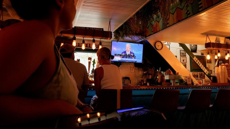 People at a restaurant called Somewhere look at a TV where U.S. President Joe Biden can be seen, on the day he announced he is stopping his bid for reelection, in Rehoboth Beach, Delaware, U.S., July 21, 2024. REUTERS/Ken Cedeno