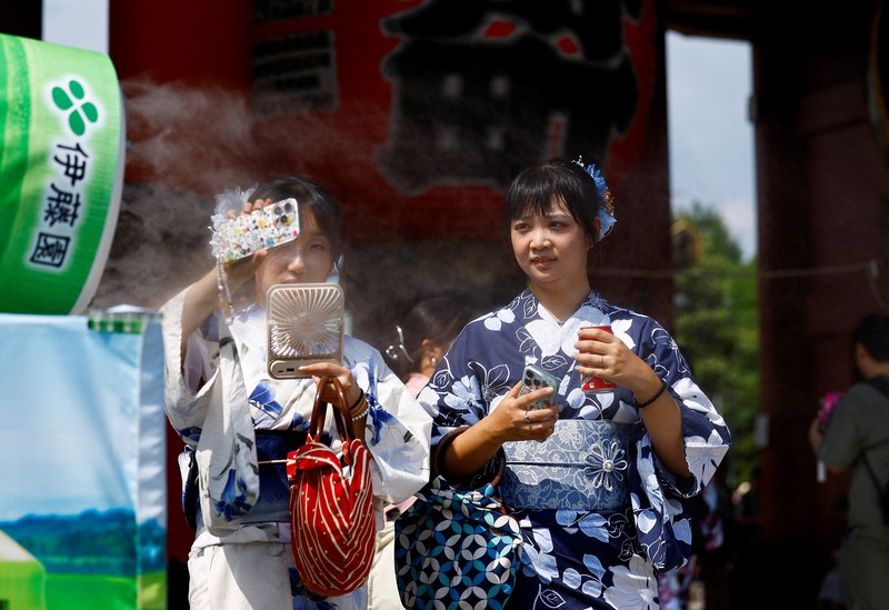 Pejalan kaki yang memegang payung berjalan di bawah sinar matahari yang terik di kuil Sensoji saat pemerintah Jepang mengeluarkan peringatan serangan panas di 39 dari 47 prefektur di Tokyo, Jepang, 22 Juli 2024. (REUTERS/Issei Kato)