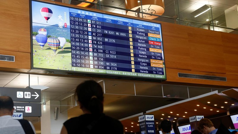 Orang-orang mengantri di dekat layar yang menampilkan informasi penerbangan di aula keberangkatan internasional Bandara Songshan Taipei saat Topan Gaemi mendekat di Taipei, Taiwan 24 Juli 2024. (REUTERS/Carlos Garcia Rawlins)