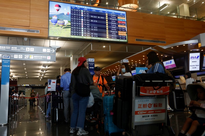 Orang-orang mengantri di dekat layar yang menampilkan informasi penerbangan di aula keberangkatan internasional Bandara Songshan Taipei saat Topan Gaemi mendekat di Taipei, Taiwan 24 Juli 2024. (REUTERS/Carlos Garcia Rawlins)