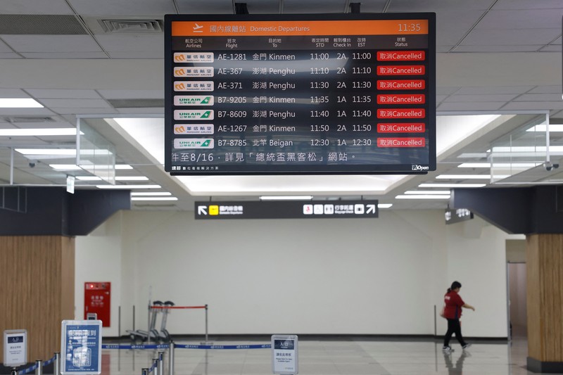 Orang-orang mengantri di dekat layar yang menampilkan informasi penerbangan di aula keberangkatan internasional Bandara Songshan Taipei saat Topan Gaemi mendekat di Taipei, Taiwan 24 Juli 2024. (REUTERS/Carlos Garcia Rawlins)