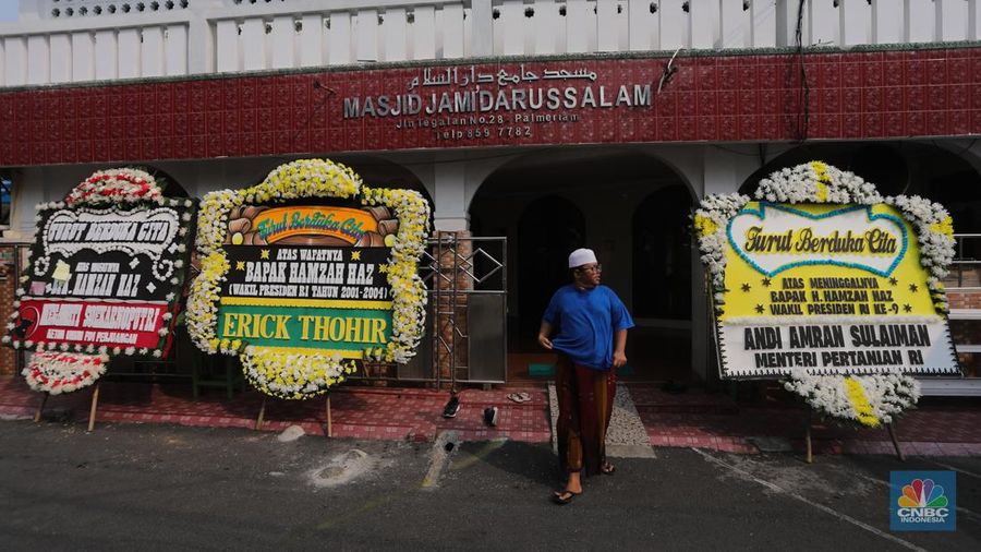 Warga berjalan di dekat karangan bunga duka cita di rumah duka Wakil Presiden ke-9 Hamzah Haz di Jalan Tegalan, Matraman, Jakarta, Rabu (24/7/2024). (CNBC Indonesia/Faisal Rahman)