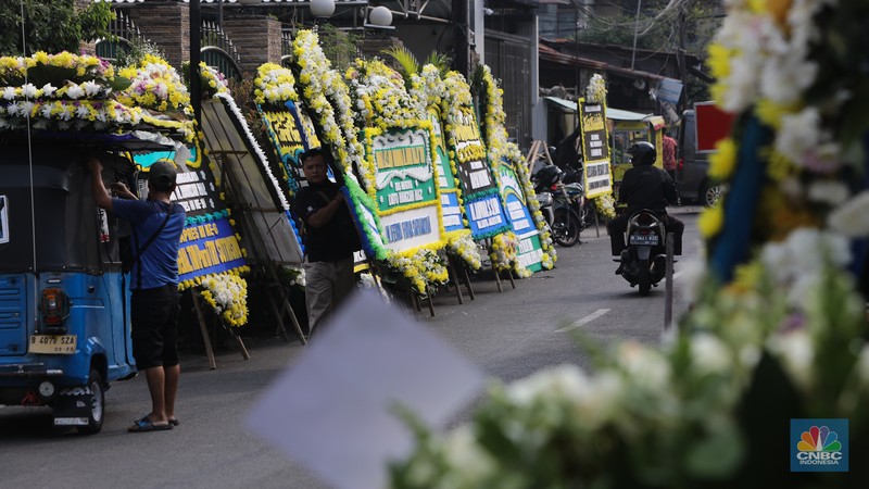 Warga berjalan di dekat karangan bunga duka cita di rumah duka Wakil Presiden ke-9 Hamzah Haz di Jalan Tegalan, Matraman, Jakarta, Rabu (24/7/2024). (CNBC Indonesia/Faisal Rahman)