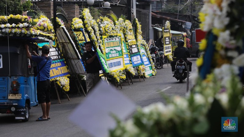 Warga berjalan di dekat karangan bunga duka cita di rumah duka Wakil Presiden ke-9 Hamzah Haz di Jalan Tegalan, Matraman, Jakarta, Rabu (24/7/2024). (CNBC Indonesia/Faisal Rahman)