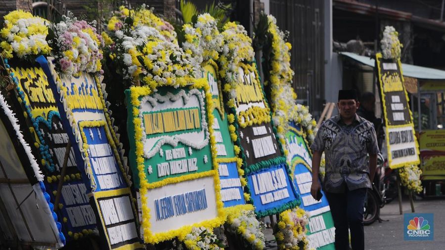 Warga berjalan di dekat karangan bunga duka cita di rumah duka Wakil Presiden ke-9 Hamzah Haz di Jalan Tegalan, Matraman, Jakarta, Rabu (24/7/2024). (CNBC Indonesia/Faisal Rahman)