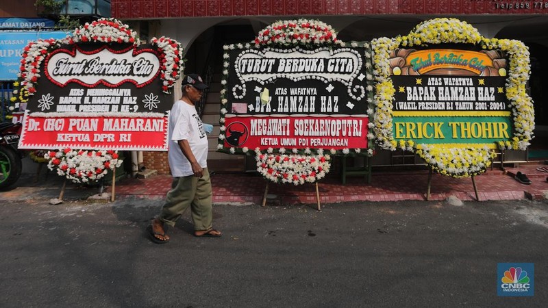 Warga berjalan di dekat karangan bunga duka cita di rumah duka Wakil Presiden ke-9 Hamzah Haz di Jalan Tegalan, Matraman, Jakarta, Rabu (24/7/2024). (CNBC Indonesia/Faisal Rahman)