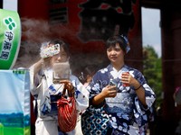 Women wearing summer kimonos take a break next to a cooling mist at the Sensoji temple as Japanese government issued heat stroke alerts in 39 of the country's 47 prefectures in Tokyo, Japan July 22, 2024.  REUTERS/Issei Kato