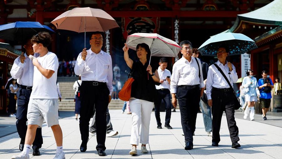 Passersby holding umbrellas walk under a strong sunlight at the Sensoji temple as Japanese government issued heat stroke alerts in 39 of the country's 47 prefectures in Tokyo, Japan July 22, 2024.  REUTERS/Issei Kato