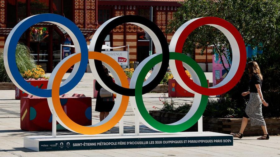 Paris 2024 Olympics - Saint-Etienne, France - July 26, 2024 A woman walks next to the Olympic Rings near the Gare de Saint-Etienne-Chateaucreux railway station after saboteurs attacked France's TGV high-speed train network ahead of the Paris 2024 Olympics. REUTERS/Thaier Al-Sudani