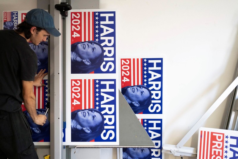 Juru cetak sablon Chris Fleury meletakkan kaus yang baru dicetak untuk mendukung kampanye kepresidenan Wakil Presiden AS Kamala Harris ke mesin pengering konveyor di Pabrik Gloo di Tucson, Arizona, AS, 25 Juli 2024. (REUTERS/Rebecca Noble)