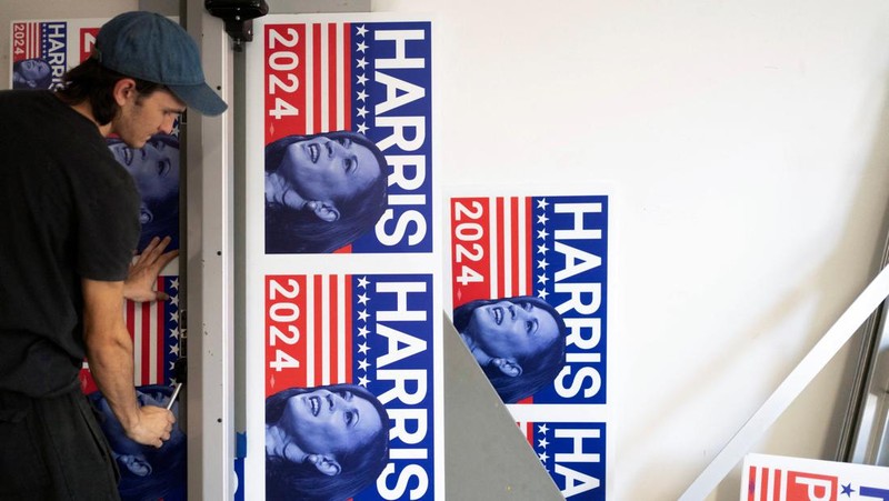 Juru cetak sablon Chris Fleury meletakkan kaus yang baru dicetak untuk mendukung kampanye kepresidenan Wakil Presiden AS Kamala Harris ke mesin pengering konveyor di Pabrik Gloo di Tucson, Arizona, AS, 25 Juli 2024. (REUTERS/Rebecca Noble)