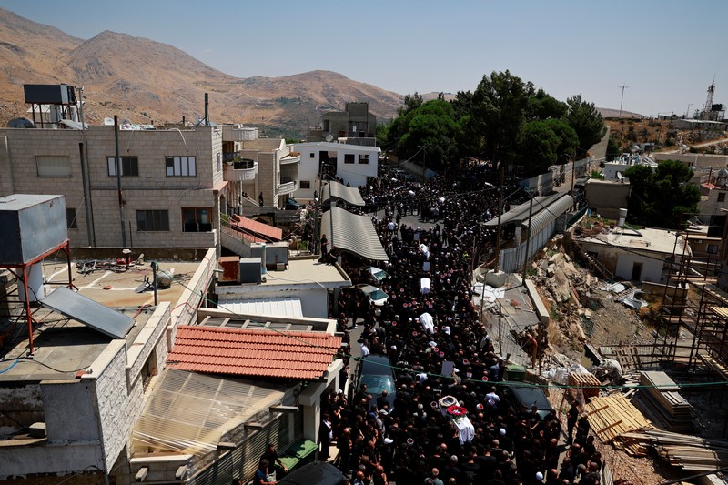 Warga berkumpul mengantarkan jenazah saat pemakaman anak-anak yang tewas pada sebuah lapangan sepak bola akibat serangan roket Hizbullah di Desa Druze, Dataran Tinggi Golan yang dikuasai Israel, Minggu (28/7/2024). (REUTERS/Ammar Awad) Warga berkumpul mengantarkan jenazah saat pemakaman anak-anak yang tewas pada sebuah lapangan sepak bola akibat serangan roket Hizbullah di Desa Druze, Dataran Tinggi Golan yang dikuasai Israel, Minggu (28/7/2024). (REUTERS/Ammar Awad)