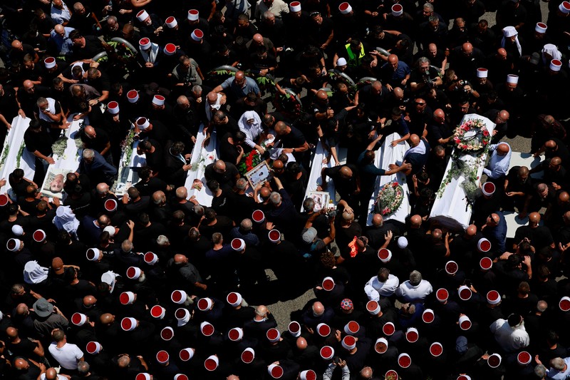 Warga berkumpul mengantarkan jenazah saat pemakaman  anak-anak yang tewas pada sebuah lapangan sepak bola akibat serangan roket Hizbullah di Desa Druze, Dataran Tinggi Golan yang dikuasai Israel, Minggu (28/7/2024). (REUTERS/Ammar Awad)
