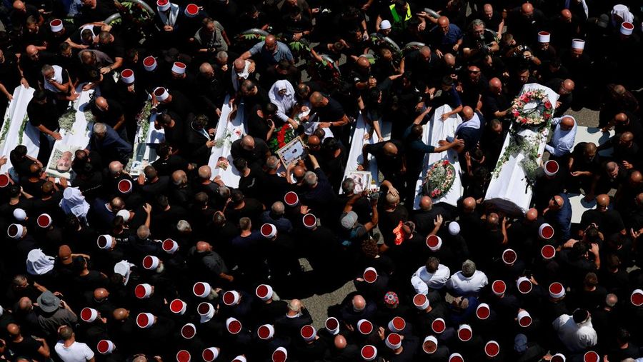 Warga berkumpul mengantarkan jenazah saat pemakaman  anak-anak yang tewas pada sebuah lapangan sepak bola akibat serangan roket Hizbullah di Desa Druze, Dataran Tinggi Golan yang dikuasai Israel, Minggu (28/7/2024). (REUTERS/Ammar Awad)