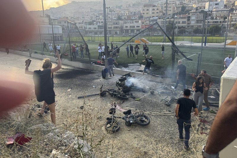 Warga menolong anak-anak yang terluka beberapa saat setelah serangan roket Hizbullah di Majdal Shams, Dataran Tinggi Golan yang diduduki Israel, Sabtu (27/7/2024). (AP Photo/Hassan Shams)
