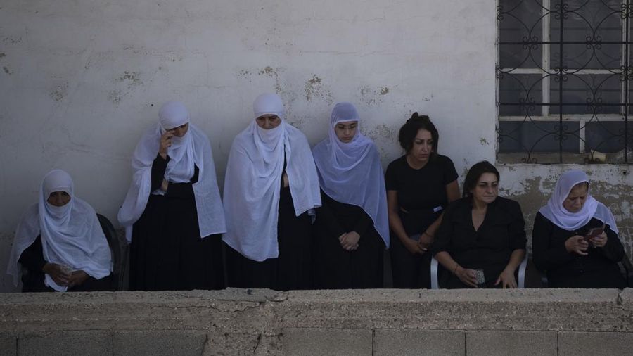 Para pelayat dari kelompok minoritas Druze menyaksikan dari balkon pemakaman sekitar 12 anak-anak dan remaja yang tewas dalam serangan roket di lapangan sepak bola di desa Majdal Shams, di Dataran Tinggi Golan yang dianeksasi Israel, Minggu, 28 Juli 2024. (AP Photo/Leo Correa)