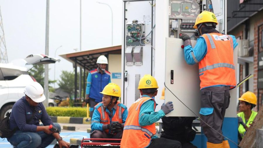 Petugas PLN tengah melakukan pemasangan dan pengintegrasian SPKLU di rest area ruas tol Mojokerto-Surabaya guna menunjang mobilitas dan kenyamanan pengguna kendaraan listrik. (Dok. PT PLN (Persero))