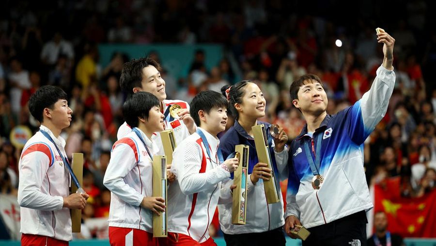 Paris 2024 Olympics - Table Tennis - Mixed Doubles Victory Ceremony - South Paris Arena 4, Paris, France - July 30, 2024. Bronze medallist Jonghoon Lim of South Korea takes selfie with Yubin Shin of South Korea and gold medallists Chuqin Wang of China and Yingsha Sun of China with silver medallists Jong Sik Ri of North Korea and Kum Yong Kim of North Korea on the podium with their medals after winning. REUTERS/Kim Hong-Ji