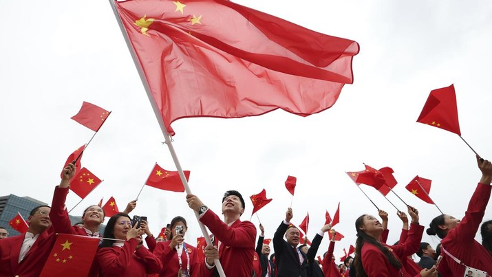 China's Olympic athletes wave national flags from a boat for the opening ceremony of the 2024 Summer Olympics on the Seine River in Paris, Friday, July 26, 2024. (Cao Can/Pool Photo via AP)