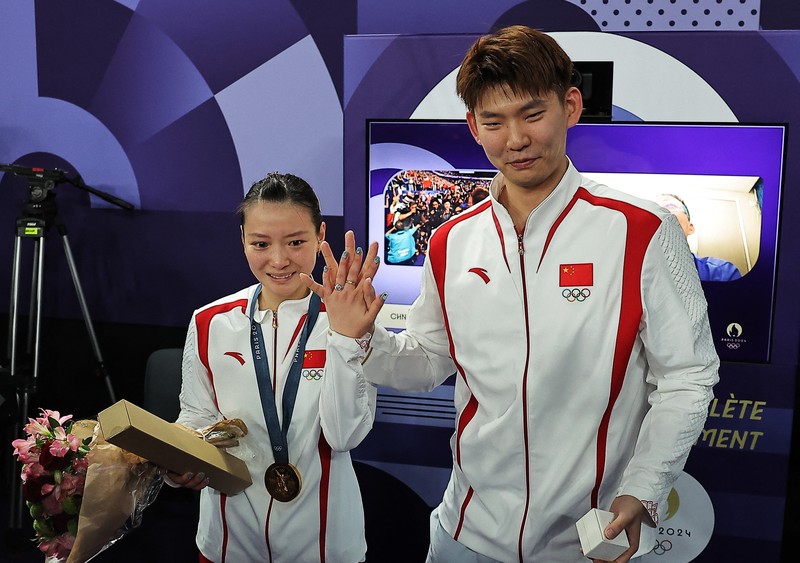 OLYMPICS-2024-BADMINTON/ Paris 2024 Olympics - Badminton - Mixed Doubles Victory Ceremony - Porte de La Chapelle Arena, Paris, France - August 02, 2024. Si Wei Zheng of China proposes to Ya Qiong Huang of China after winning the gold. REUTERS/Ann Wang