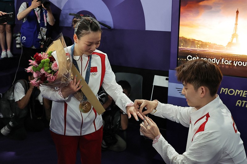 OLYMPICS-2024-BADMINTON/ Paris 2024 Olympics - Badminton - Mixed Doubles Victory Ceremony - Porte de La Chapelle Arena, Paris, France - August 02, 2024. Si Wei Zheng of China proposes to Ya Qiong Huang of China after winning the gold. REUTERS/Ann Wang