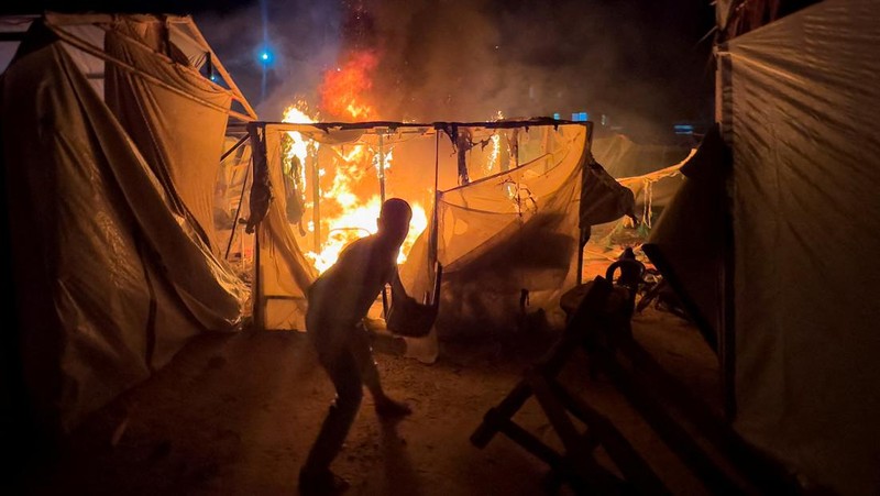 Warga Palestina bekerja memadamkan api di lokasi serangan Israel terhadap kamp tenda bagi para pengungsi, di tengah konflik Israel-Hamas, di Deir Al-Balah di Jalur Gaza tengah, 4 Agustus 2024. (REUTERS/Abdullah Al-Attar)