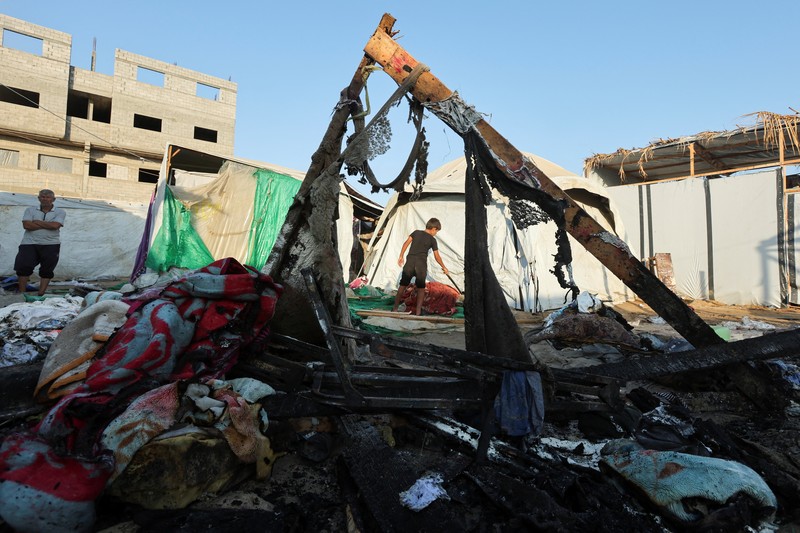 Warga Palestina bekerja memadamkan api di lokasi serangan Israel terhadap kamp tenda bagi para pengungsi, di tengah konflik Israel-Hamas, di Deir Al-Balah di Jalur Gaza tengah, 4 Agustus 2024. Warga Palestina bekerja memadamkan api di lokasi serangan Israel terhadap kamp tenda bagi para pengungsi, di tengah konflik Israel-Hamas, di Deir Al-Balah di Jalur Gaza tengah, 4 Agustus 2024. (REUTERS/Abdullah Al-Attar)