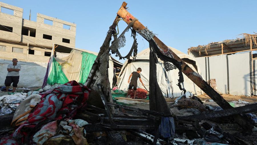 Warga Palestina bekerja memadamkan api di lokasi serangan Israel terhadap kamp tenda bagi para pengungsi, di tengah konflik Israel-Hamas, di Deir Al-Balah di Jalur Gaza tengah, 4 Agustus 2024. (REUTERS/Abdullah Al-Attar)