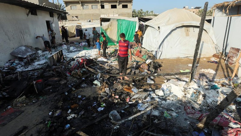 Warga Palestina bekerja memadamkan api di lokasi serangan Israel terhadap kamp tenda bagi para pengungsi, di tengah konflik Israel-Hamas, di Deir Al-Balah di Jalur Gaza tengah, 4 Agustus 2024. (REUTERS/Abdullah Al-Attar)