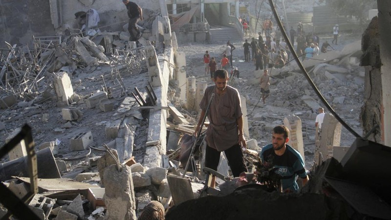 Warga Palestina memeriksa lokasi serangan Israel terhadap sekolah yang melindungi orang-orang terlantar, di tengah konflik Israel-Hamas, di Kota Gaza, 3 Agustus 2024. (REUTERS/Mahmoud Issa)