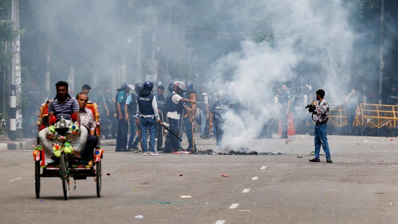 Pria berlari melewati pusat perbelanjaan yang dibakar oleh pengunjuk rasa selama unjuk rasa menentang Perdana Menteri Sheikh Hasina dan pemerintahannya yang menuntut keadilan bagi para korban yang tewas dalam bentrokan mematikan baru-baru ini di seluruh negeri, di Dhaka, Bangladesh, Minggu, 4 Agustus 2024. (AP Photo/Rajib Dhar)
