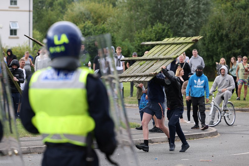 Petugas polisi berdiri di hadapan para demonstran selama protes anti-imigrasi, di Rotherham, Inggris, 4 Agustus 2024. Petugas polisi berdiri di hadapan para demonstran selama protes anti-imigrasi, di Rotherham, Inggris, 4 Agustus 2024. (REUTERS/Hollie Adams)