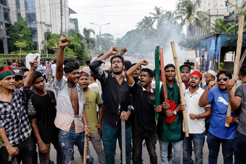 Pria berlari melewati pusat perbelanjaan yang dibakar oleh pengunjuk rasa selama unjuk rasa menentang Perdana Menteri Sheikh Hasina dan pemerintahannya yang menuntut keadilan bagi para korban yang tewas dalam bentrokan mematikan baru-baru ini di seluruh negeri, di Dhaka, Bangladesh, Minggu, 4 Agustus 2024. (AP Photo/Rajib Dhar)