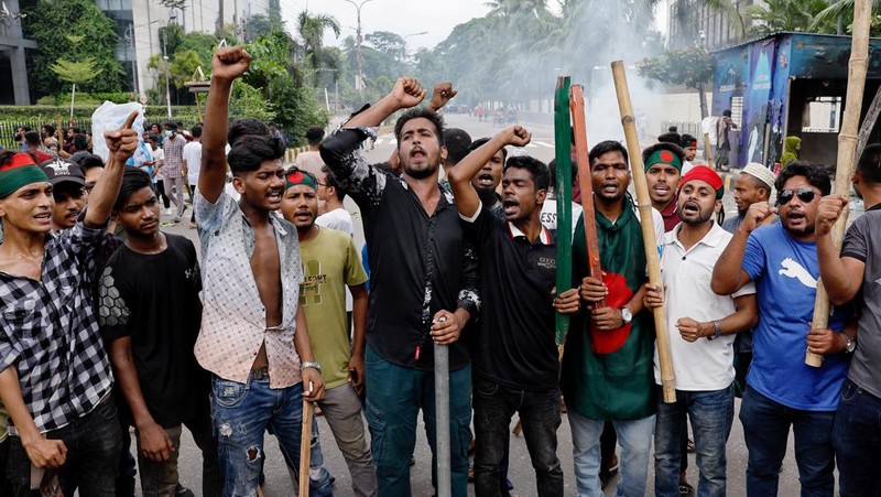 Pria berlari melewati pusat perbelanjaan yang dibakar oleh pengunjuk rasa selama unjuk rasa menentang Perdana Menteri Sheikh Hasina dan pemerintahannya yang menuntut keadilan bagi para korban yang tewas dalam bentrokan mematikan baru-baru ini di seluruh negeri, di Dhaka, Bangladesh, Minggu, 4 Agustus 2024. (AP Photo/Rajib Dhar)