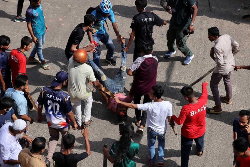 Pria berlari melewati pusat perbelanjaan yang dibakar oleh pengunjuk rasa selama unjuk rasa menentang Perdana Menteri Sheikh Hasina dan pemerintahannya yang menuntut keadilan bagi para korban yang tewas dalam bentrokan mematikan baru-baru ini di seluruh negeri, di Dhaka, Bangladesh, Minggu, 4 Agustus 2024. (AP Photo/Rajib Dhar)