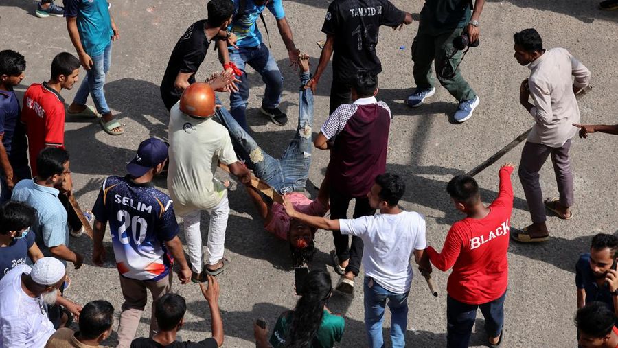 Pria berlari melewati pusat perbelanjaan yang dibakar oleh pengunjuk rasa selama unjuk rasa menentang Perdana Menteri Sheikh Hasina dan pemerintahannya yang menuntut keadilan bagi para korban yang tewas dalam bentrokan mematikan baru-baru ini di seluruh negeri, di Dhaka, Bangladesh, Minggu, 4 Agustus 2024. (AP Photo/Rajib Dhar)