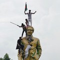 Orang-orang memanjat patung Sheikh Mujibur Rahman di kawasan Bijoy Sarani, saat merayakan pengunduran diri Perdana Menteri Sheikh Hasina di Dhaka, Bangladesh, 5 Agustus 2024. (REUTERS/Mohammad Ponir Hossain)