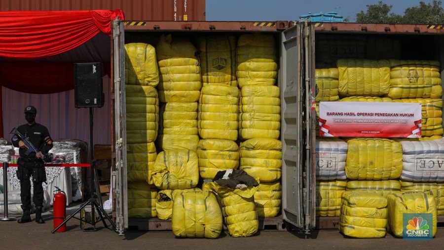 Petugas Bea Cukai berjaga disamping pakain bekas (balpres) di Tempat Penimbunan Pabean (TPP) Bea dan Cukai, Cikarang, Kabupaten Bekasi, Jawa Barat, Selasa (6/8/2024). (CNBC Indonesia/Faisal Rahman)