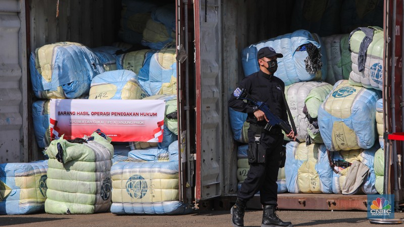 Petugas Bea Cukai berjaga disamping pakain bekas (balpres) di Tempat Penimbunan Pabean (TPP) Bea dan Cukai, Cikarang, Kabupaten Bekasi, Jawa Barat, Selasa (6/8/2024). (CNBC Indonesia/Faisal Rahman)