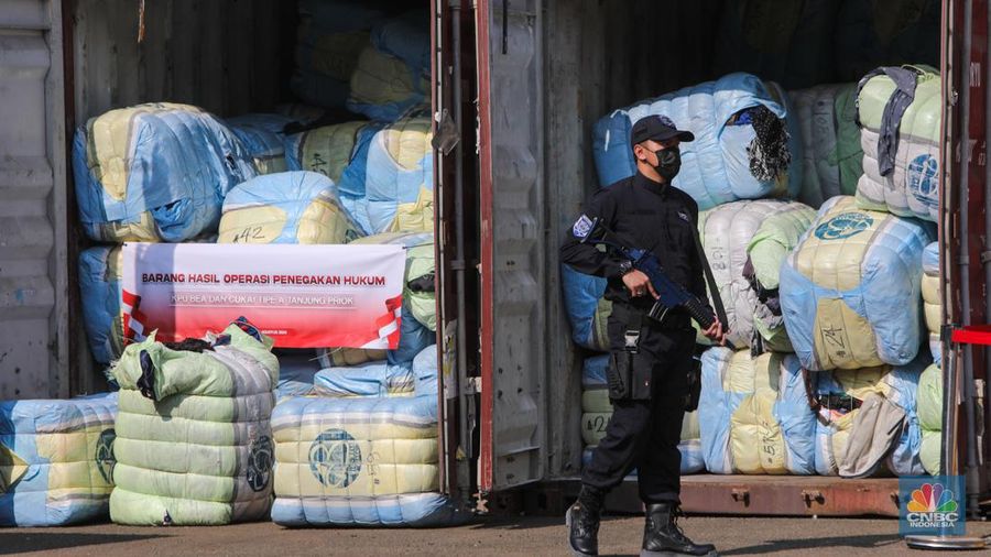Petugas Bea Cukai berjaga disamping pakain bekas (balpres) di Tempat Penimbunan Pabean (TPP) Bea dan Cukai, Cikarang, Kabupaten Bekasi, Jawa Barat, Selasa (6/8/2024). (CNBC Indonesia/Faisal Rahman)