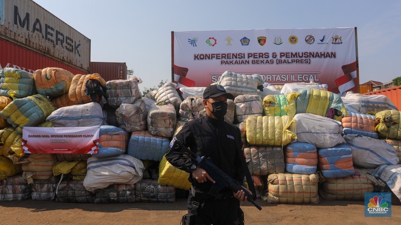 Petugas Bea Cukai berjaga disamping pakain bekas (balpres) di Tempat Penimbunan Pabean (TPP) Bea dan Cukai, Cikarang, Kabupaten Bekasi, Jawa Barat, Selasa (6/8/2024). (CNBC Indonesia/Faisal Rahman)
