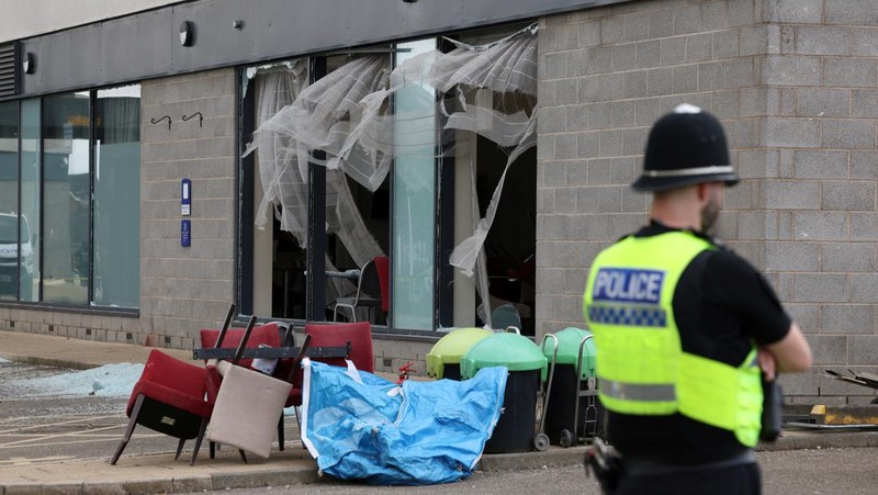 Seorang petugas polisi berjalan di luar hotel Holiday Inn Express setelah perusuh menyerang gedung tersebut di Rotherham, Inggris, 5 Agustus 2024. Pemerintah mengatakan gedung tersebut digunakan oleh pencari suaka. (REUTERS/Hollie Adams)