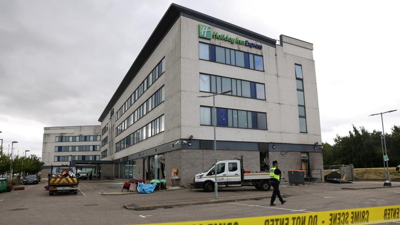 Seorang petugas polisi berjalan di luar hotel Holiday Inn Express setelah perusuh menyerang gedung tersebut di Rotherham, Inggris, 5 Agustus 2024. Pemerintah mengatakan gedung tersebut digunakan oleh pencari suaka. (REUTERS/Hollie Adams)