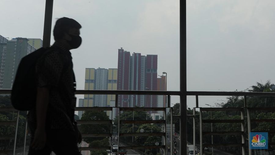 Pejalan kaki melintasi jembatan penyebrangan orang (JPO) dengan latar Wisma Atlet Kemayoran di Jakarta, Kamis (8/8/2024). (CNBC Indonesia/Faisal Rahman)