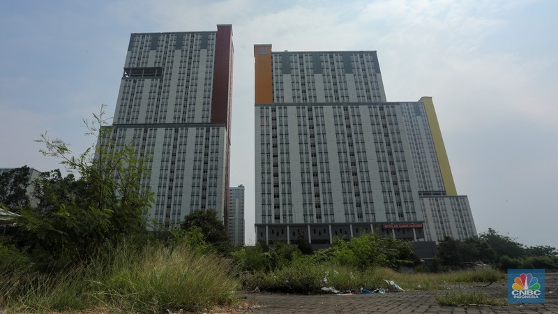 Pejalan kaki melintasi jembatan penyebrangan orang (JPO) dengan latar Wisma Atlet Kemayoran di Jakarta, Kamis (8/8/2024). (CNBC Indonesia/Faisal Rahman)
