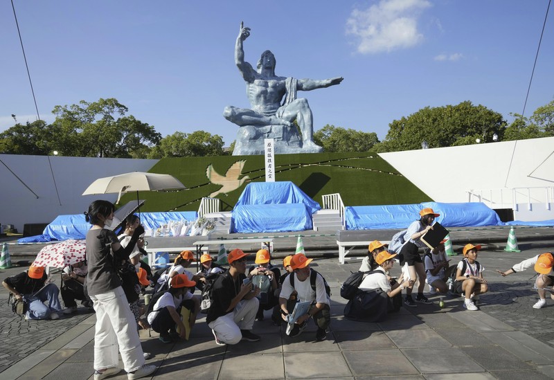 Pengunjung Taman Perdamaian berjongkok saat peringatan gempa bumi dikeluarkan di Nagasaki, Jepang bagian barat, Kamis, 8 Agustus 2024. (Kyodo News via AP)