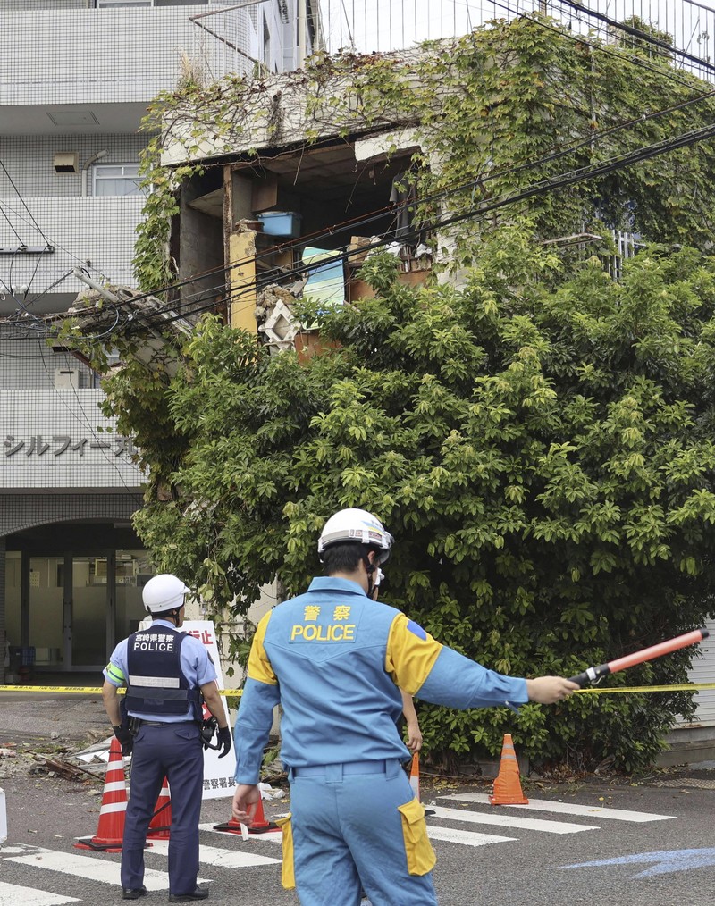 Pengunjung Taman Perdamaian berjongkok saat peringatan gempa bumi dikeluarkan di Nagasaki, Jepang bagian barat, Kamis, 8 Agustus 2024. (Kyodo News via AP)