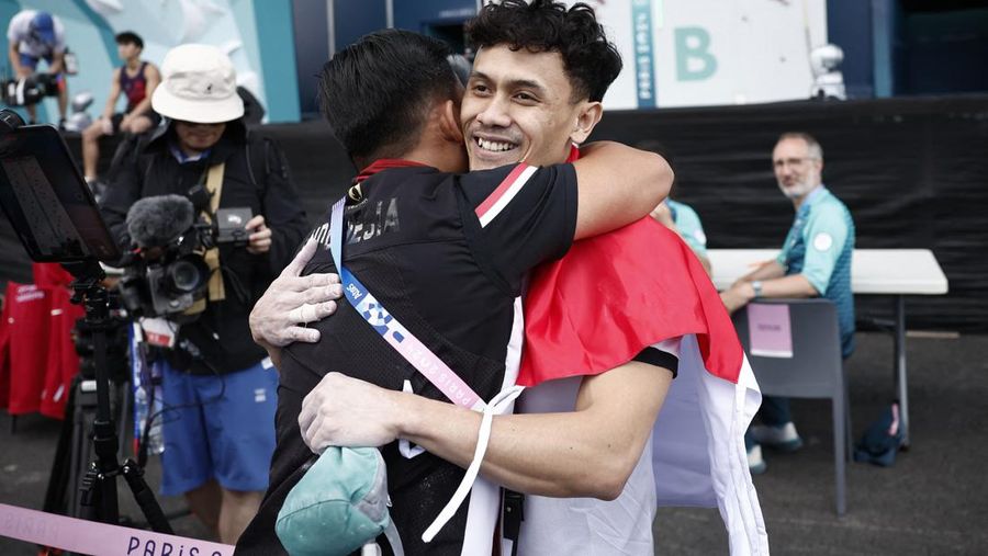 Veddriq Leonardo mengibarkan bendera Indonesia usai berhasil meraih medali emas pertama buat Indonesia usai mengalahkan Wu Peng pada final nomor speed panjat tebing di Le Boruget Climbing Venue, Kamis (8/8/2024). (REUTERS/Benoit Tessier)
