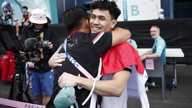 Veddriq Leonardo mengibarkan bendera Indonesia usai berhasil meraih medali emas pertama buat Indonesia usai mengalahkan Wu Peng pada final nomor speed panjat tebing di Le Boruget Climbing Venue, Kamis (8/8/2024). (REUTERS/Benoit Tessier)