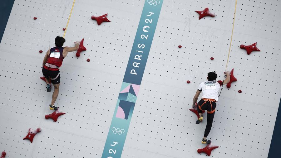 Veddriq Leonardo mengibarkan bendera Indonesia usai berhasil meraih medali emas pertama buat Indonesia usai mengalahkan Wu Peng pada final nomor speed panjat tebing di Le Boruget Climbing Venue, Kamis (8/8/2024). (REUTERS/Benoit Tessier)